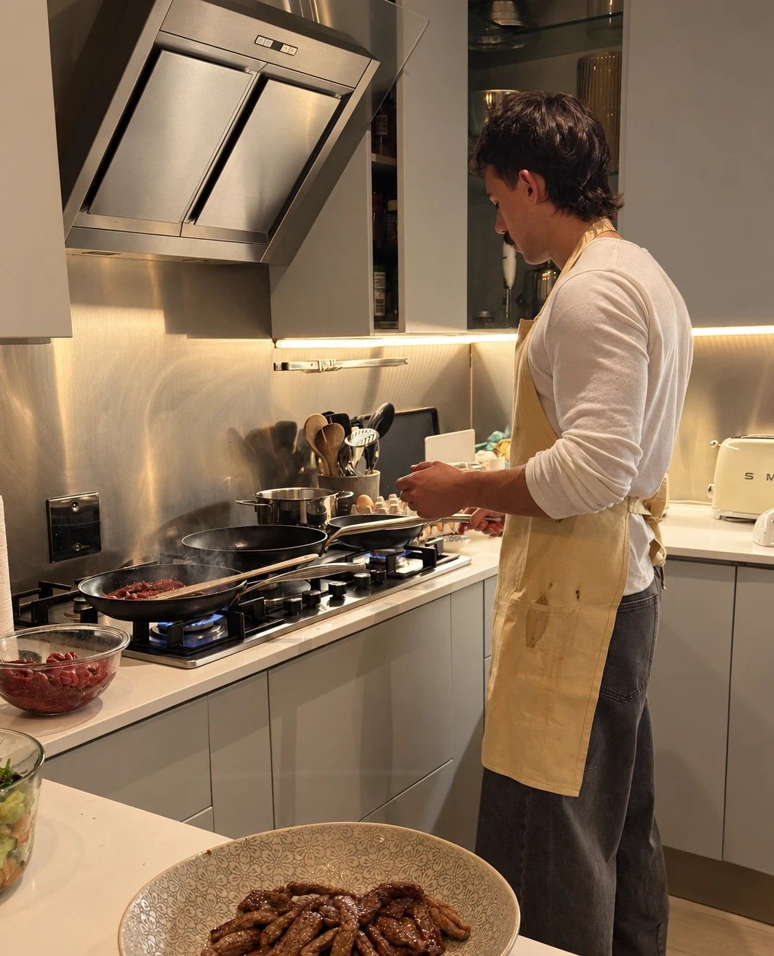Matthew cooking at a stove with three pans going