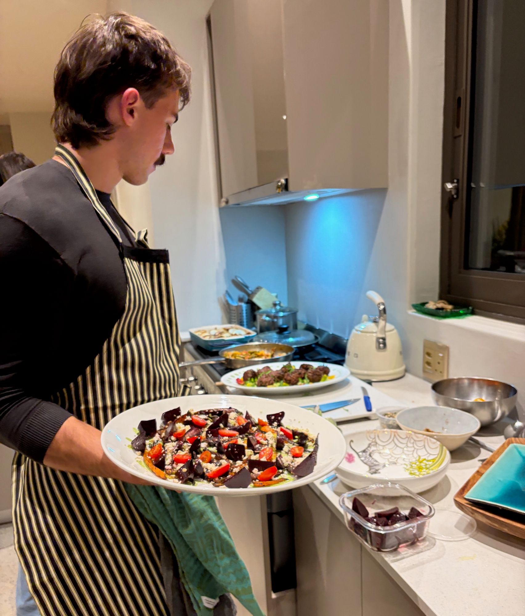 Matthew carrying a beetroot salad through a villa kitchen