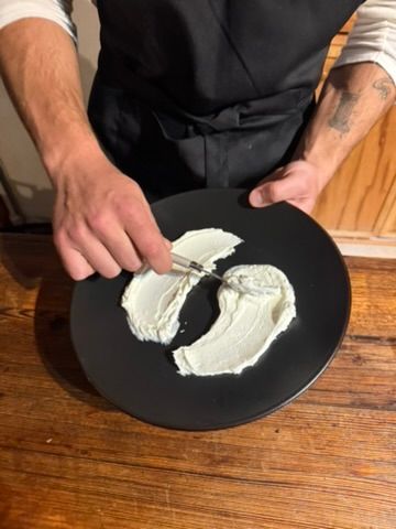 Spreading whipped cheese across a black plate