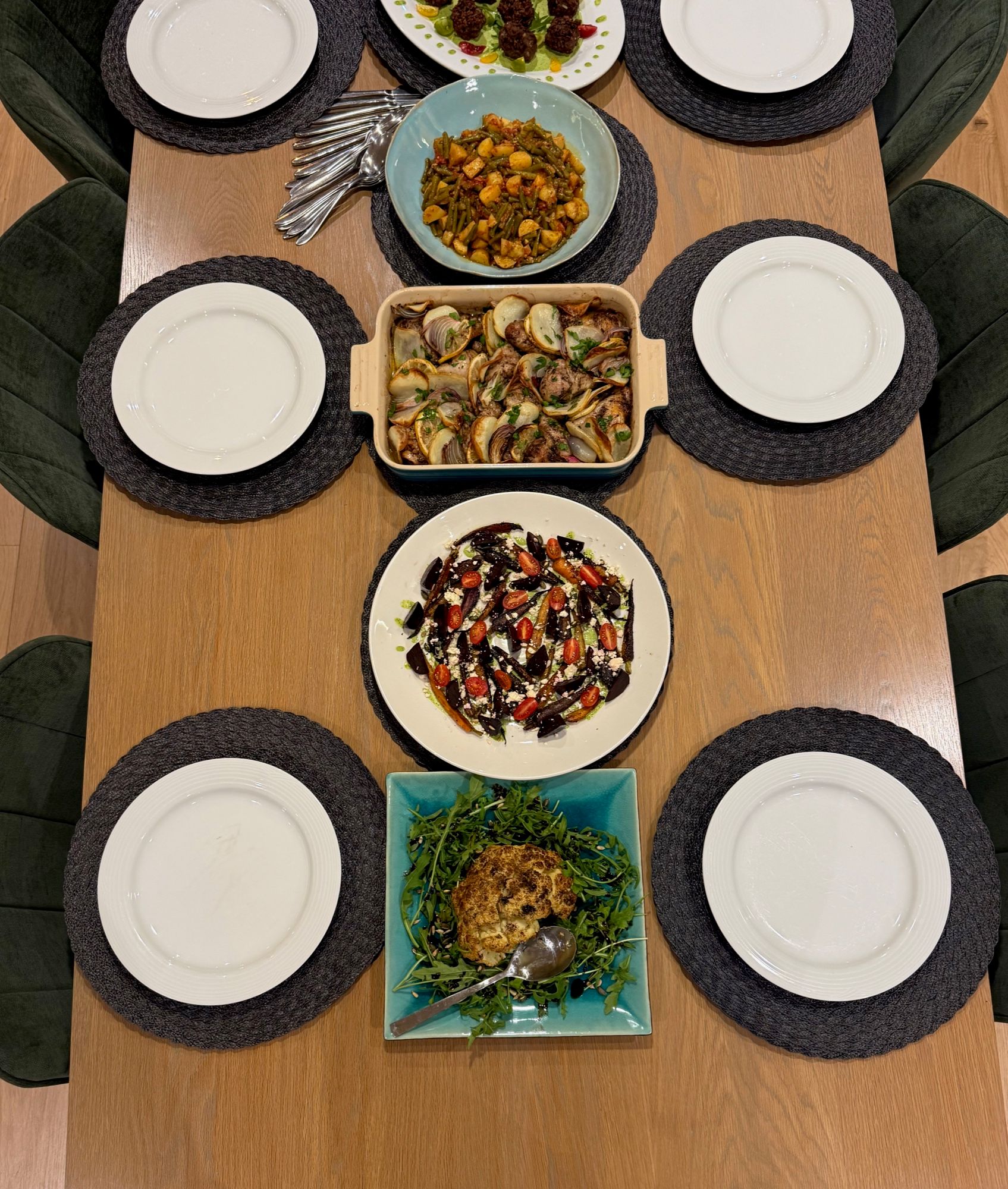 A table laid for six with a beetroot and feta salad, a potato and onion bake, green beans, meatballs and roast cauliflower